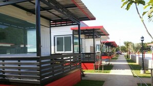 A modern building with a red and white facade, large windows, and a covered outdoor area. - Cape Go Resort (Tha Mai)