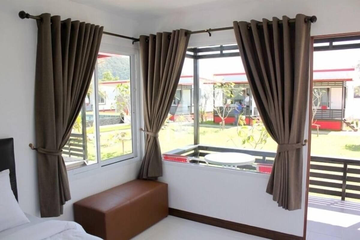 A room with a bed, a bench, and a window with curtains.