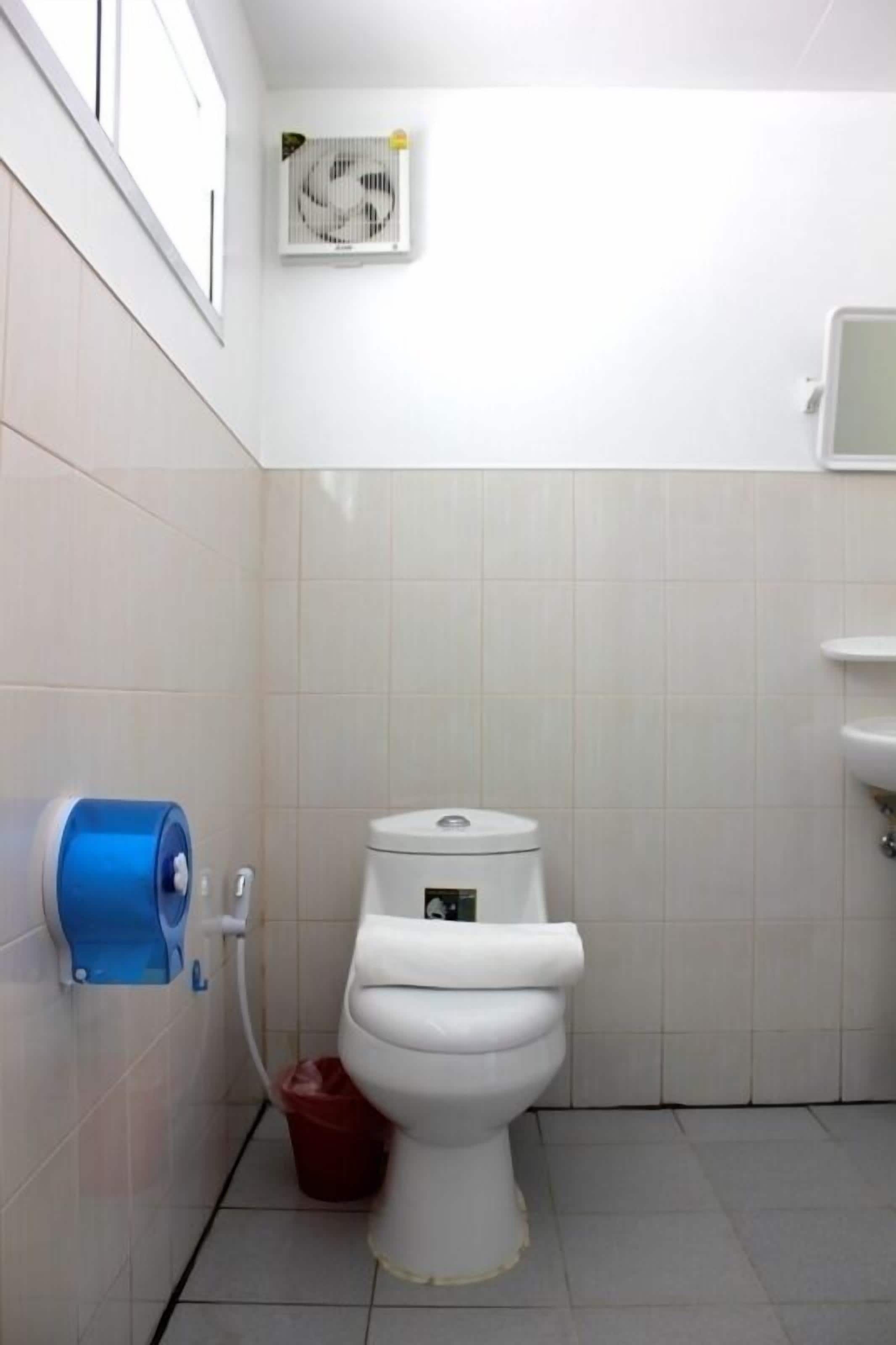 Un baño pequeño y limpio con inodoro, un secador de manos azul y un lavabo blanco.
