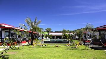 A hotel with multiple red-roofed buildings, a central pool area, and well-maintained tropical landscaping.