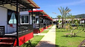 A row of single-story cabins with a covered walkway, each with a small porch and a window. - Cape Go Resort (Tha Mai)