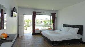 A bedroom with a bed, a TV, a bathroom, and a view of the outside. - Cape Go Resort (Tha Mai)