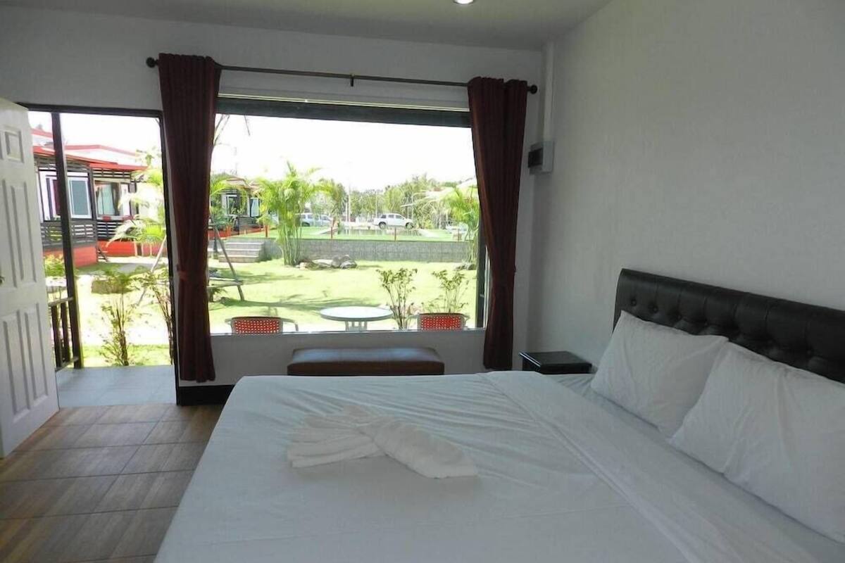 A hotel room with a bed, a small table, and a view of the outdoor area.