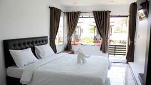 A neatly made bed with white linens and a white towel sculpture on the bed. - Cape Go Resort (Tha Mai)
