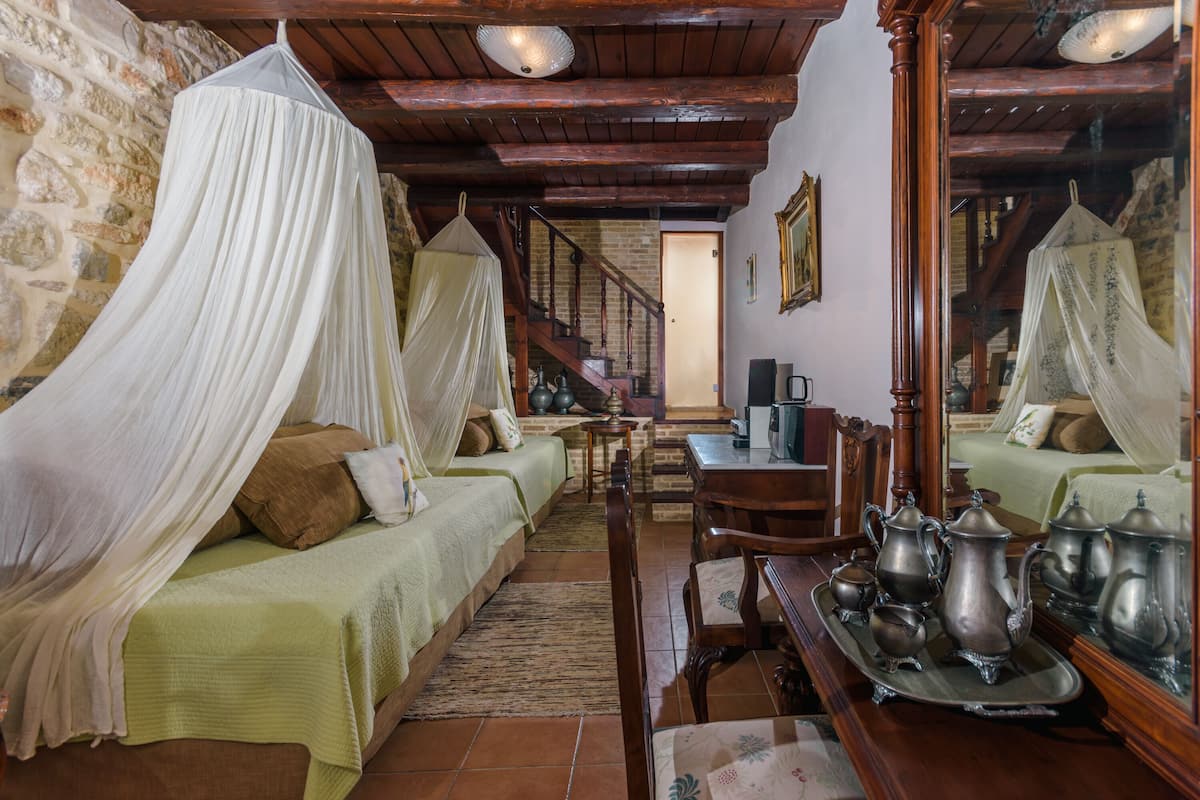 A traditional room with a stone wall, a wooden staircase, and a bed with a canopy.