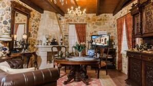 A rustic room with stone walls, a wooden ceiling, a chandelier, a fireplace, and antique furniture. - Casa Di Veneto (Hersonissos)