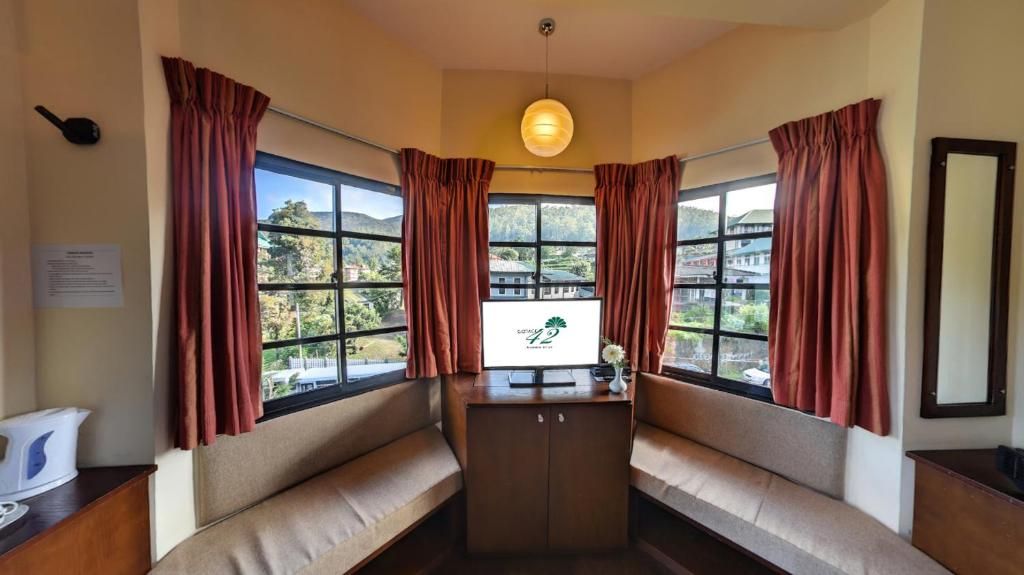 A room with a view of a mountainous landscape through large windows, a wooden cabinet, and a bench.