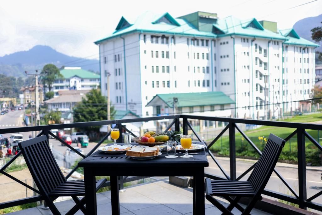 A balcony with a table set for breakfast, overlooking a large building with green roofs.