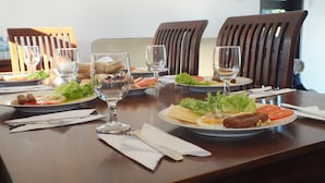 Een gedekte eettafel met borden eten, glazen en bestek.