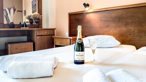Une chambre d’hôtel avec un lit, une bouteille de champagne et un verre posé sur le lit.