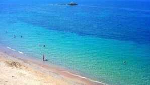 Une plage avec une eau turquoise cristalline et un rivage sablonneux.