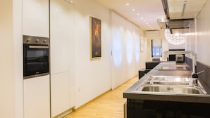 Una cocina moderna con electrodomésticos integrados, un lavamanos de acero inoxidable y una zona de comedor con barra.