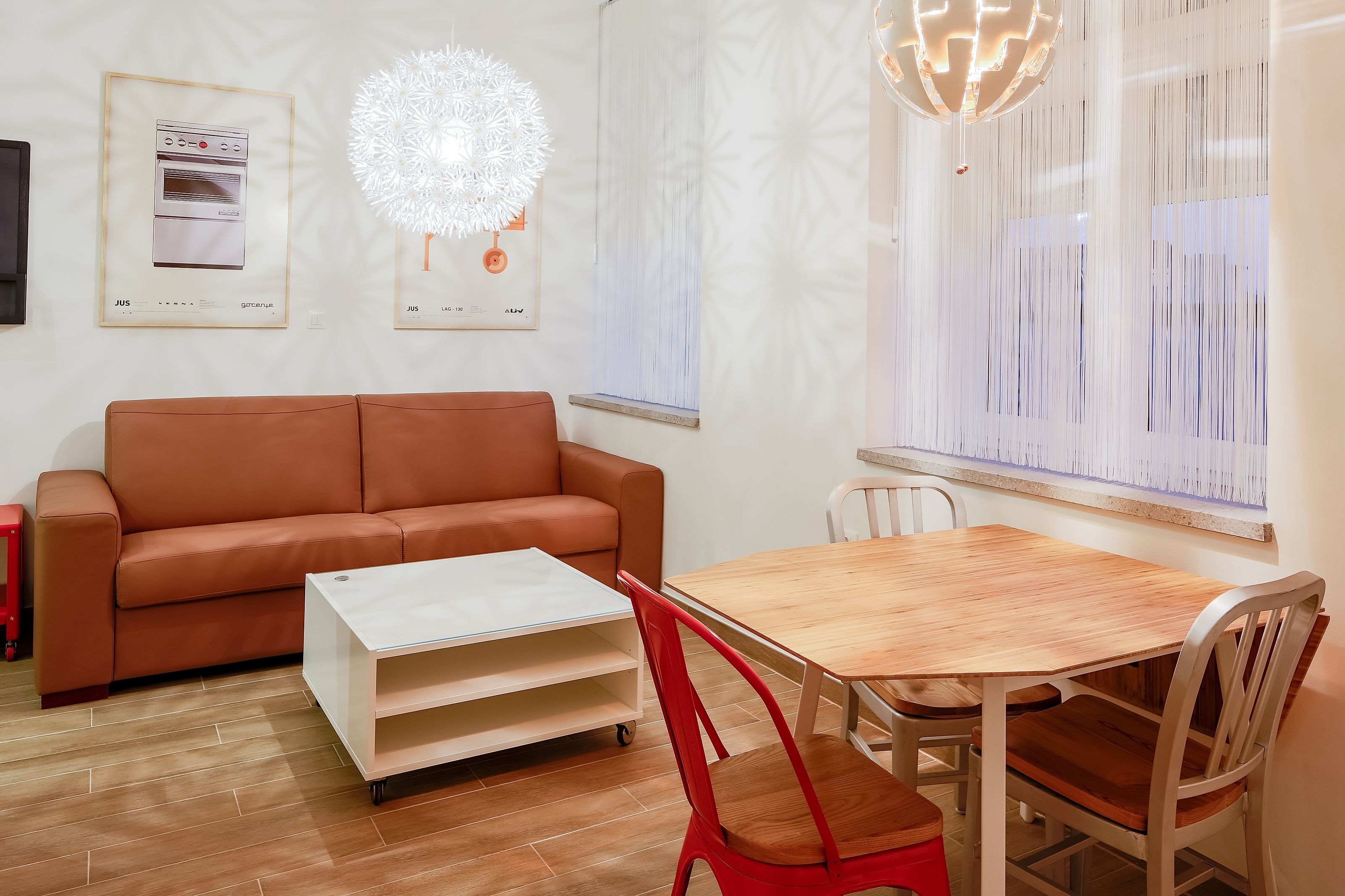 A modern living room with a brown sofa, a wooden dining table, and a white coffee table.