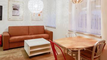 Una sala moderna con un sofá marrón, una mesa de comedor de madera y una mesa de centro blanca.