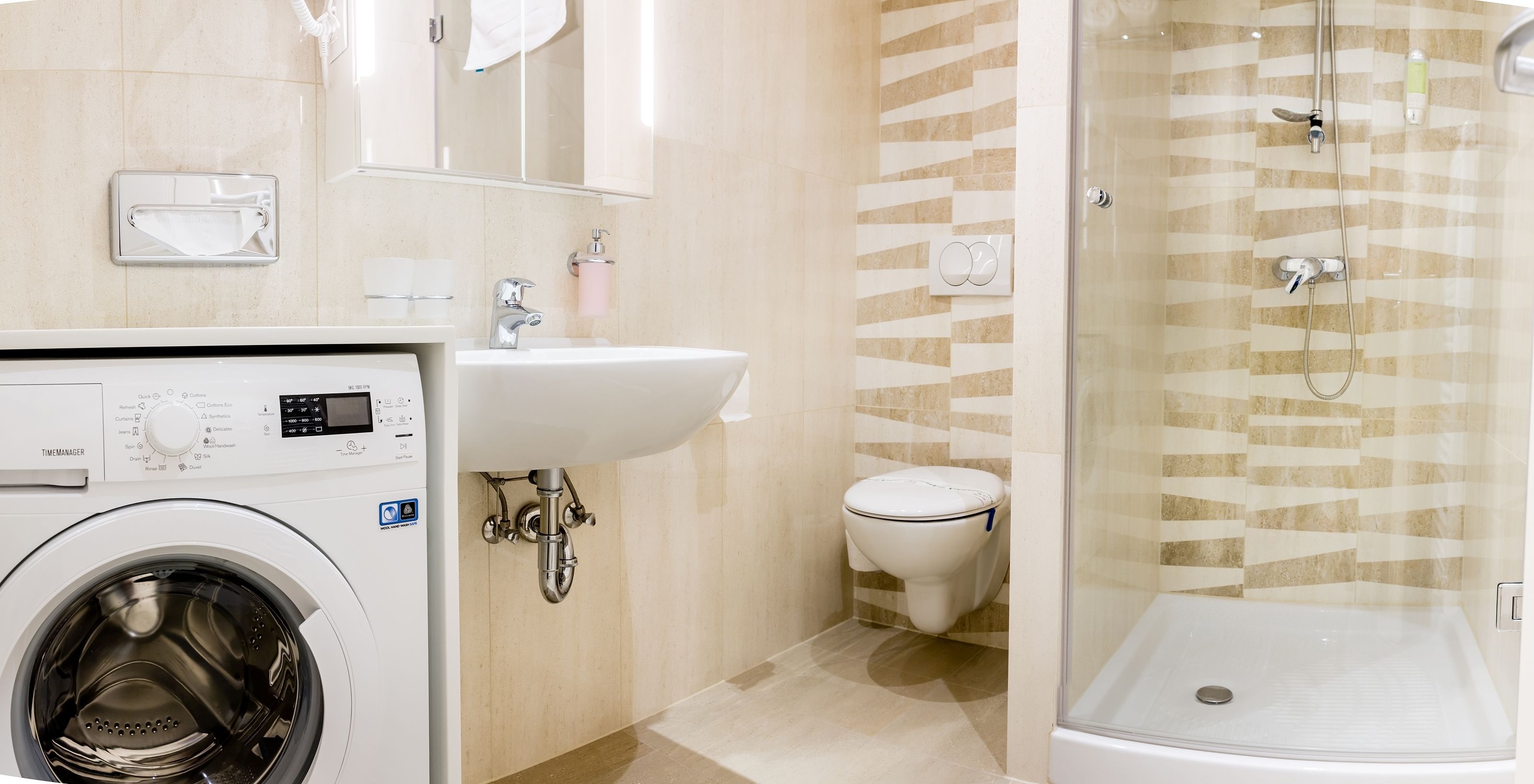 A modern bathroom with a washing machine, sink, toilet, and glass-enclosed shower.