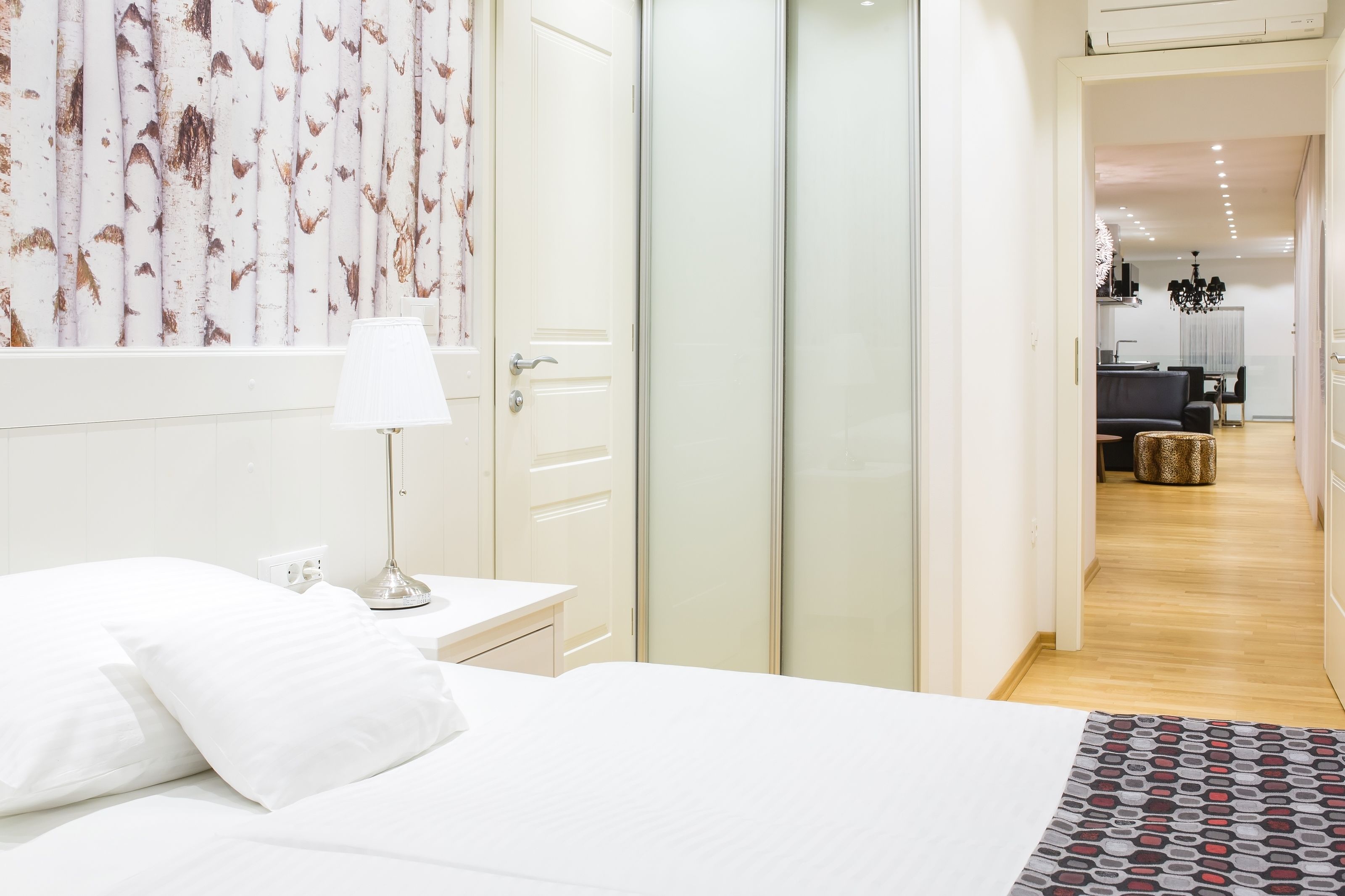 A bedroom with a bed, bedside table, lamp, and a wardrobe.