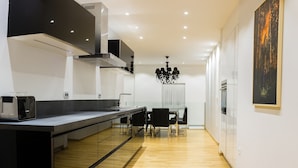 Una cocina moderna con encimera negra, suelo de madera y una zona de comedor con candelabro.