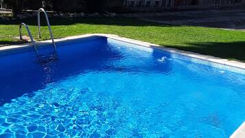Een rechthoekig zwembad met helderblauw water en een metalen ladder aan de zijkant.