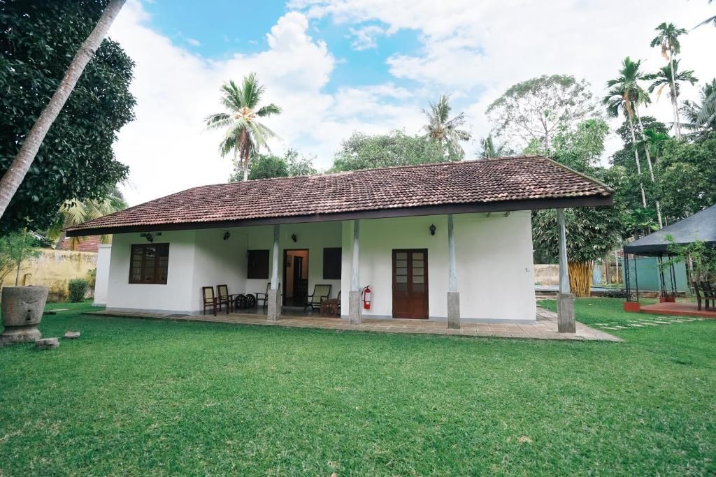 A single-story building with a tiled roof, a covered porch, and a small garden area.