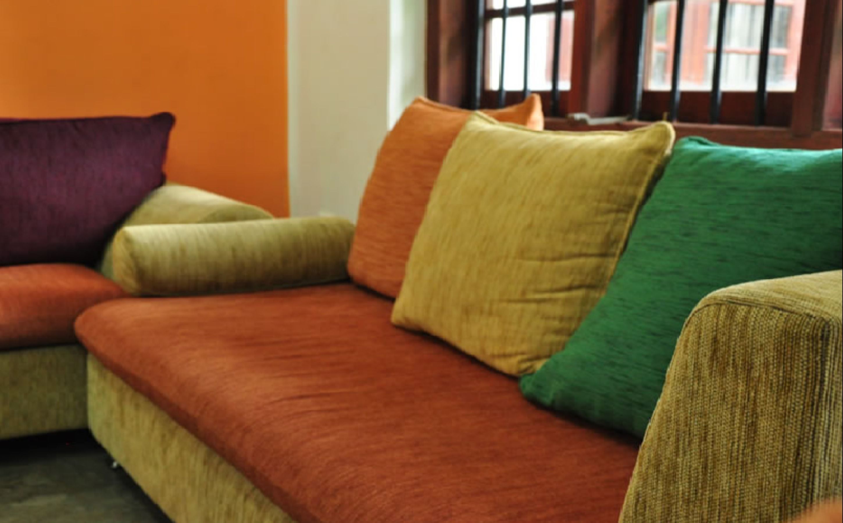 A sofa with multiple cushions in various colors.