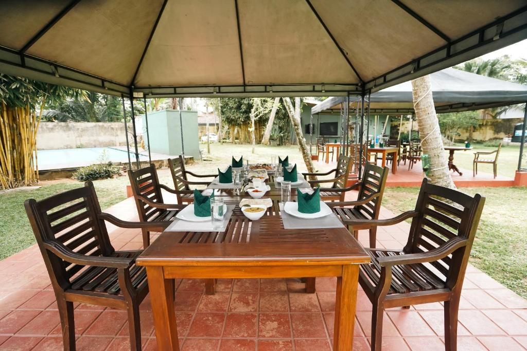 An outdoor dining area with a covered table and chairs, surrounded by a garden view.