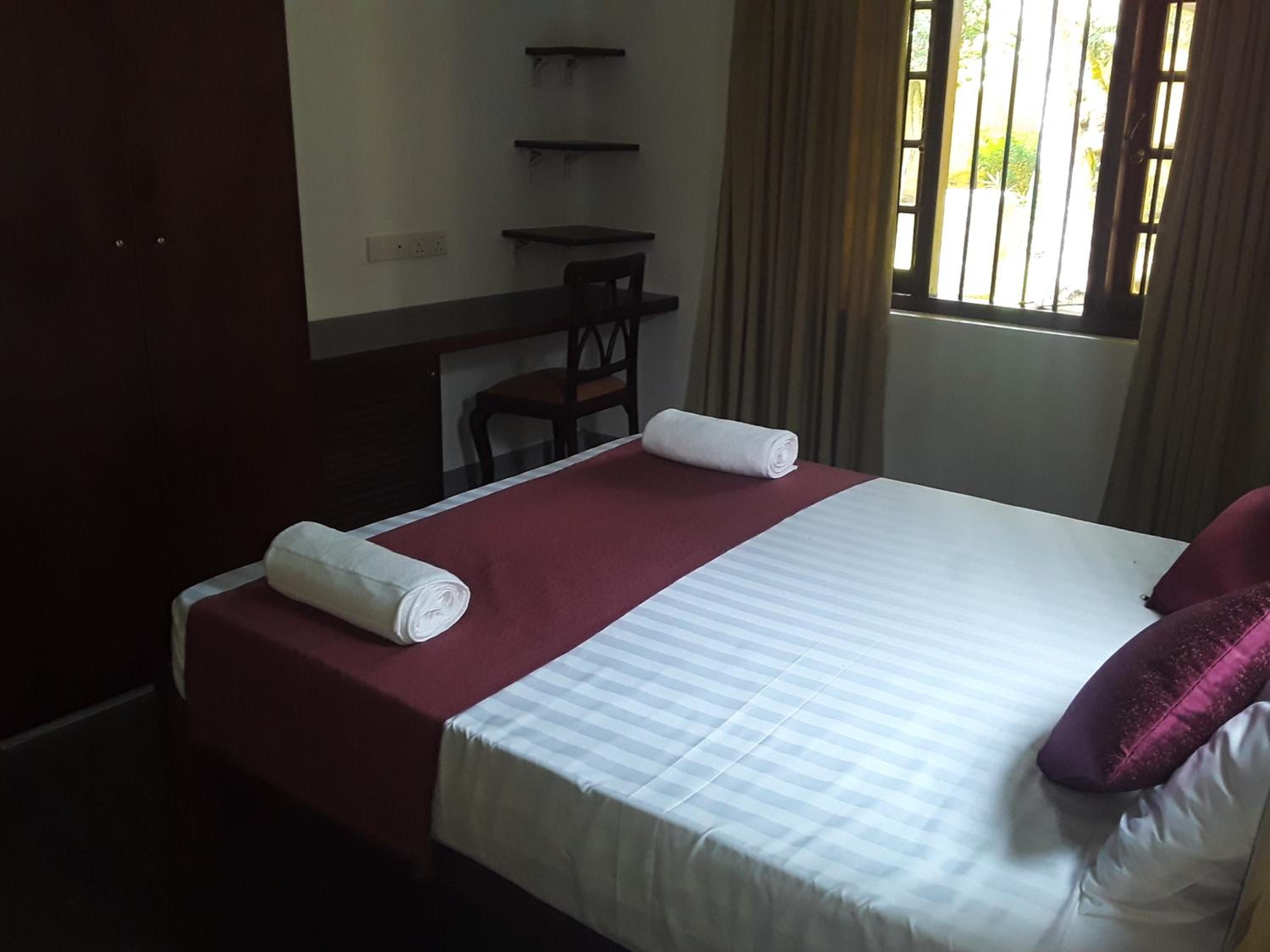 A hotel room with a bed, a desk, a chair, and a window with curtains.