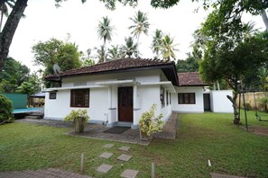 A two-story white building with a tiled roof, a front porch, and a small garden area with potted plants. - Gedara Resort (Wadduwa)