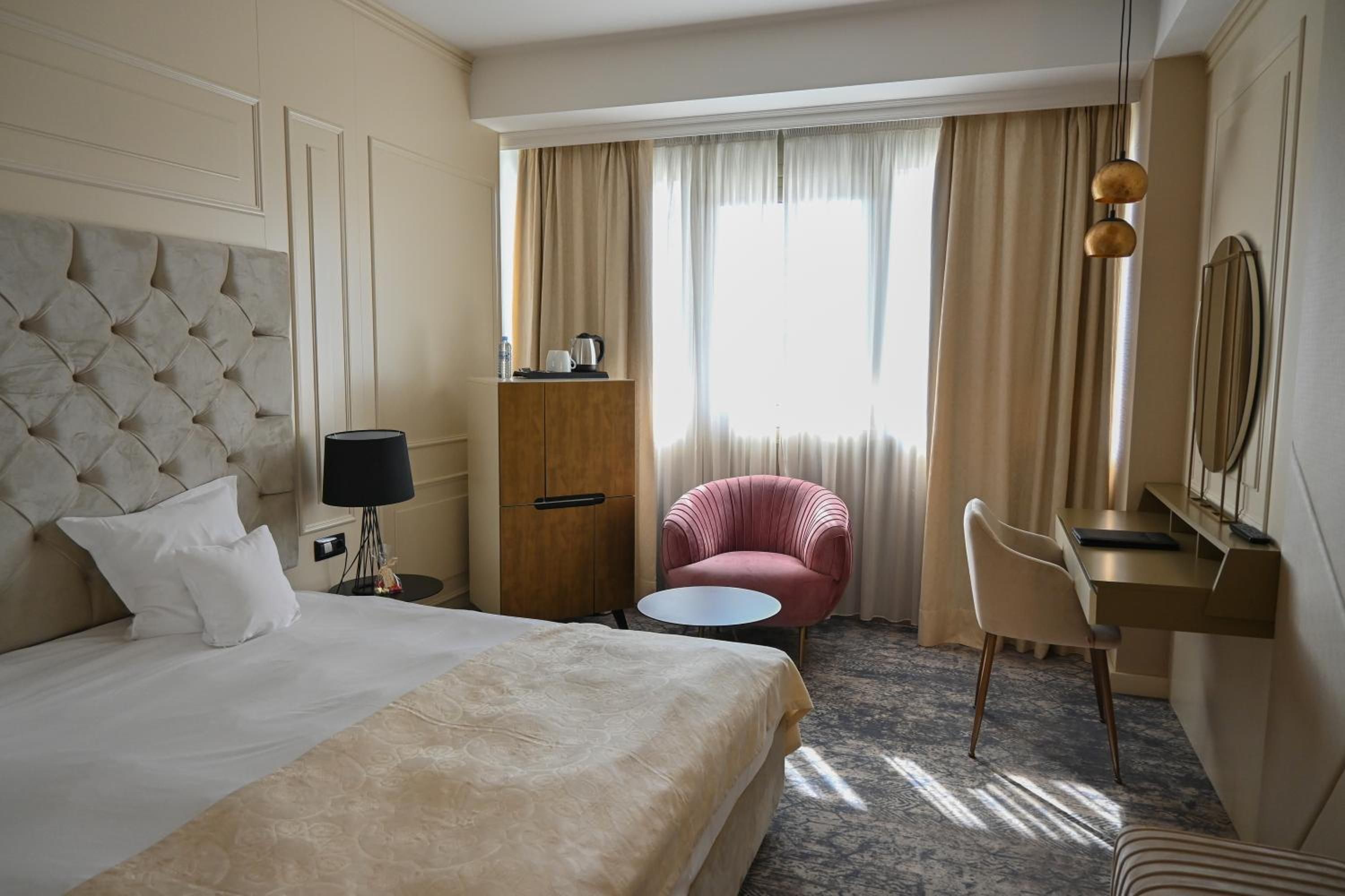 Una habitación de hotel con una cama grande, un escritorio, una silla, una mesita y un armario.
