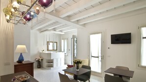 Uma área de refeições com mesa, cadeiras, um vaso de flores e um candelabro.