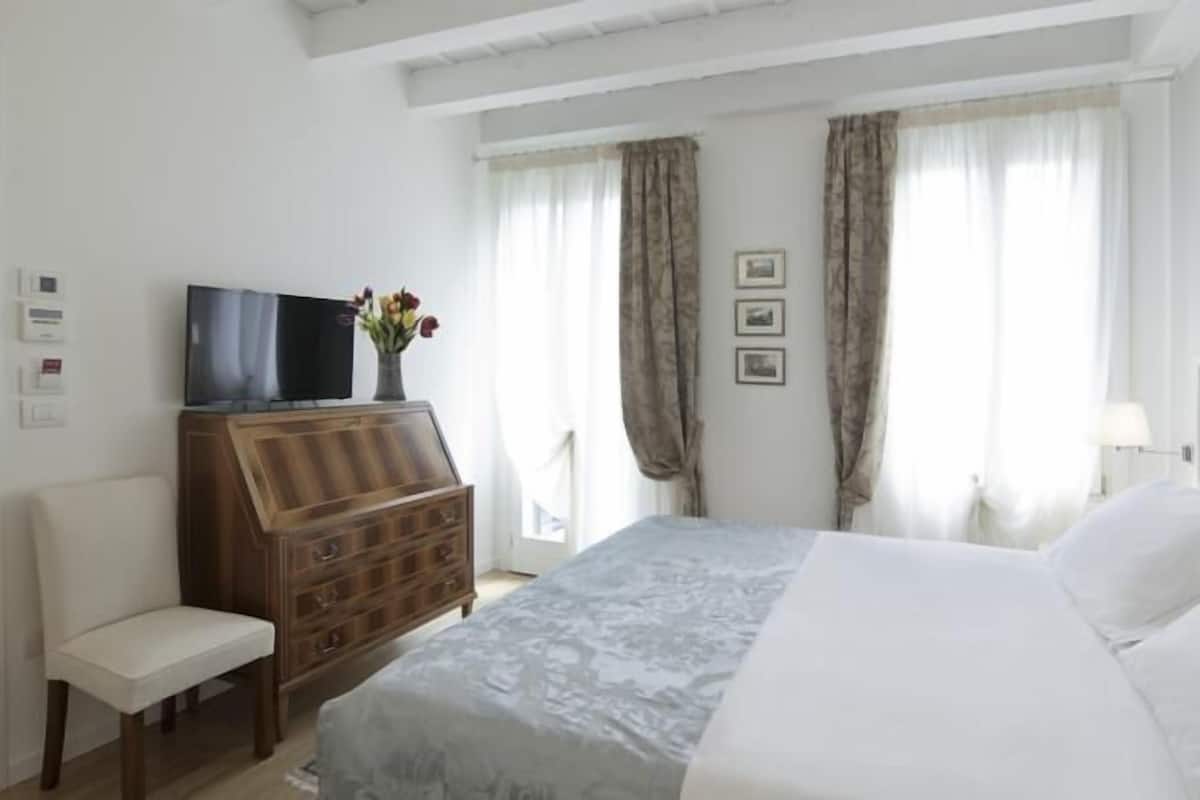 A hotel room with a bed, a wooden dresser, a television, and a chair.
