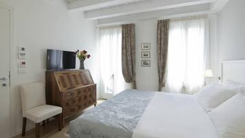 Una habitación de hotel con una cama, un aparador de madera, un televisor y una silla.