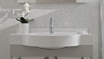 A modern bathroom with a white sink, chrome faucet, and a potted orchid.