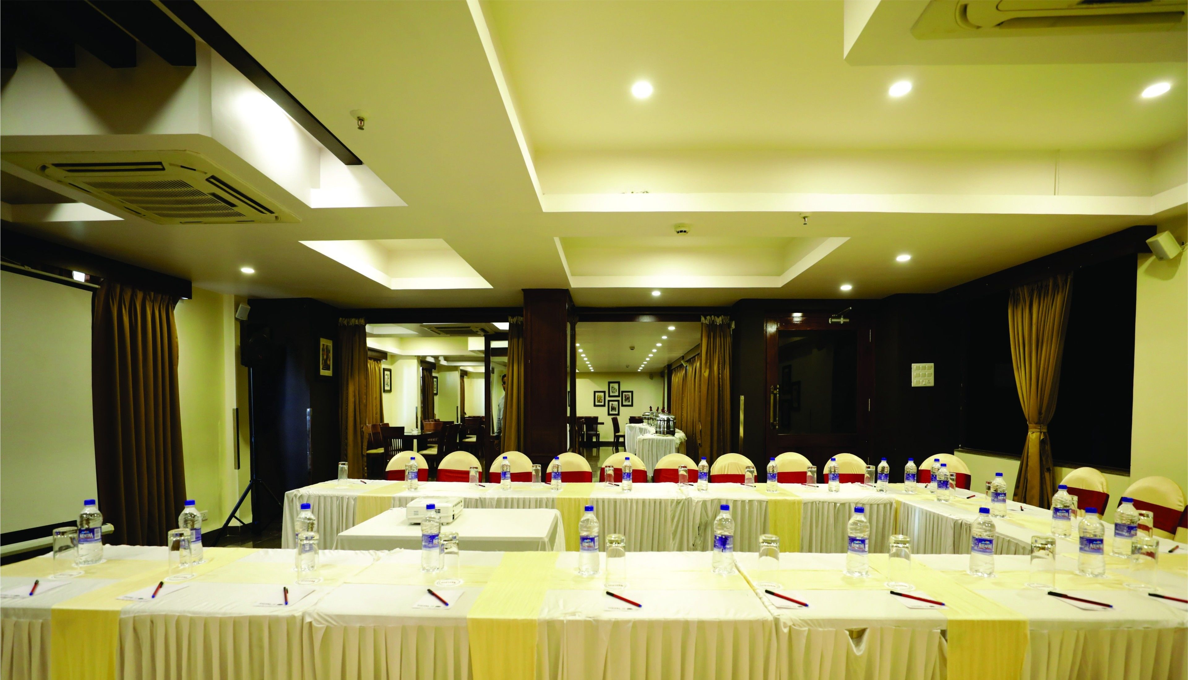 A conference room with multiple tables, each equipped with nameplates, water bottles, and pens.