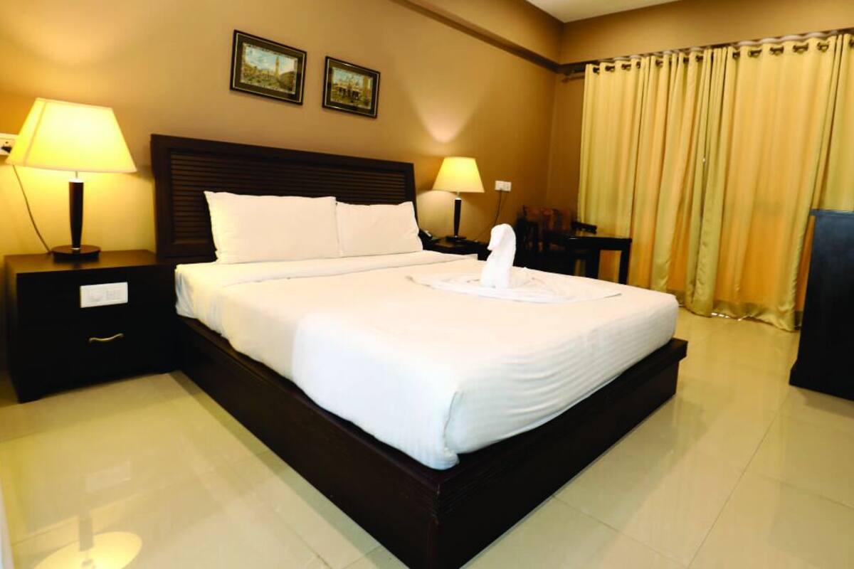 A hotel room with a large bed, two bedside tables with lamps, a desk, and a chair.