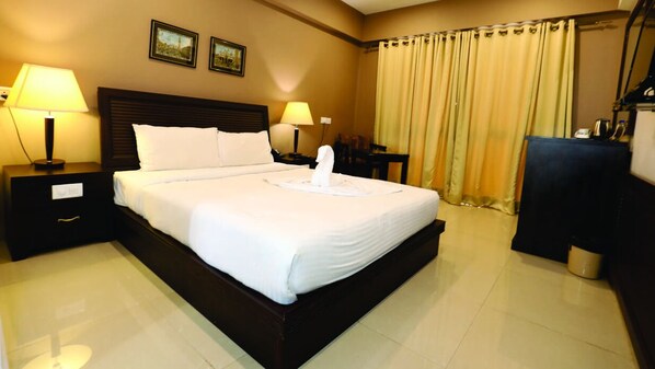 A hotel room with a large bed, two bedside tables with lamps, a desk, and a chair. - Seasons Hotel & Convention Center (Margao)