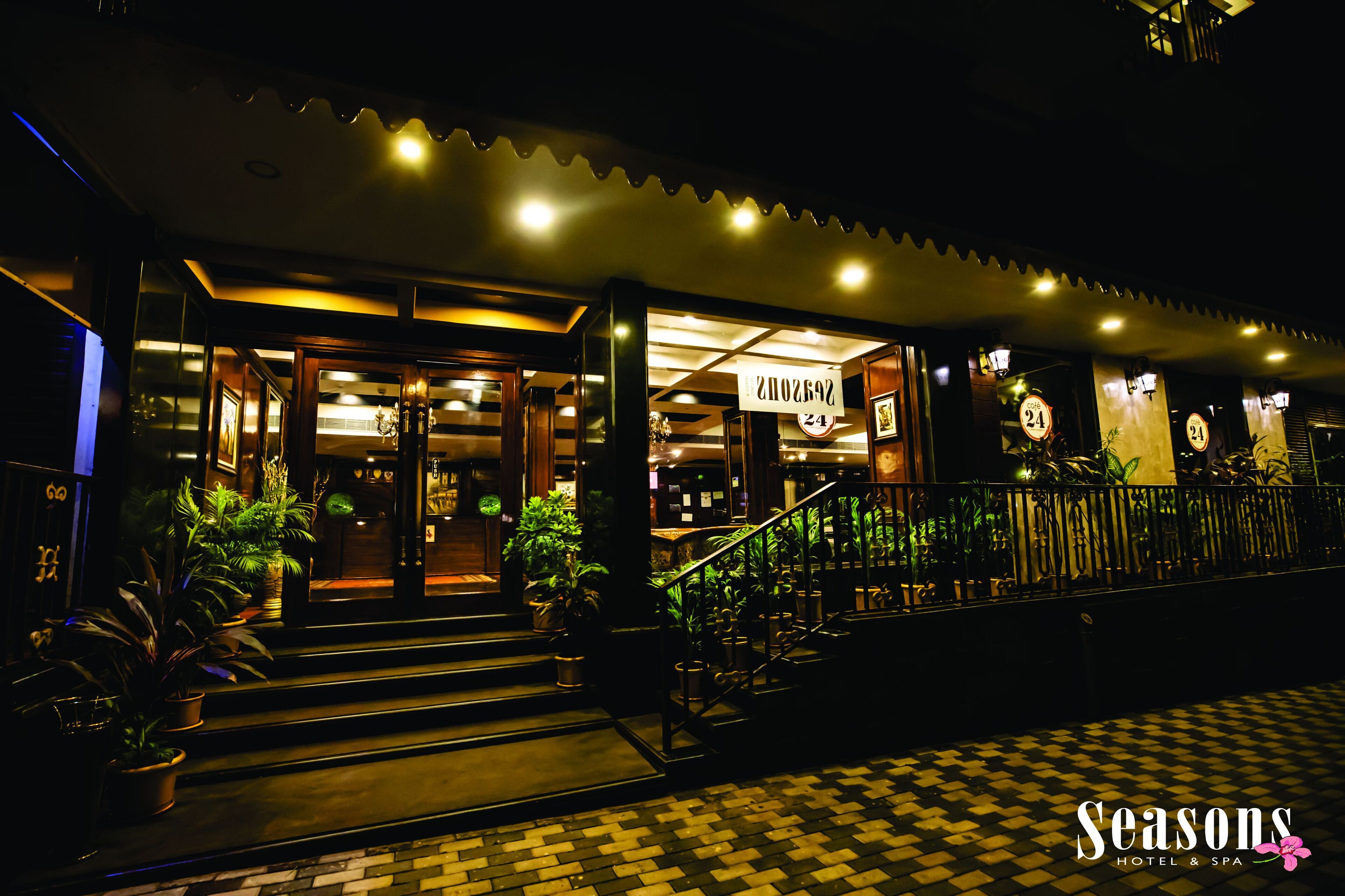 A hotel entrance with a checkered floor, potted plants, and a staircase leading to the entrance.