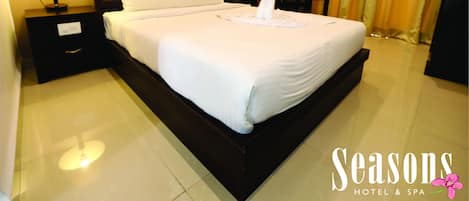 A hotel room with a large bed, two bedside tables with lamps, a headboard, and a curtain.