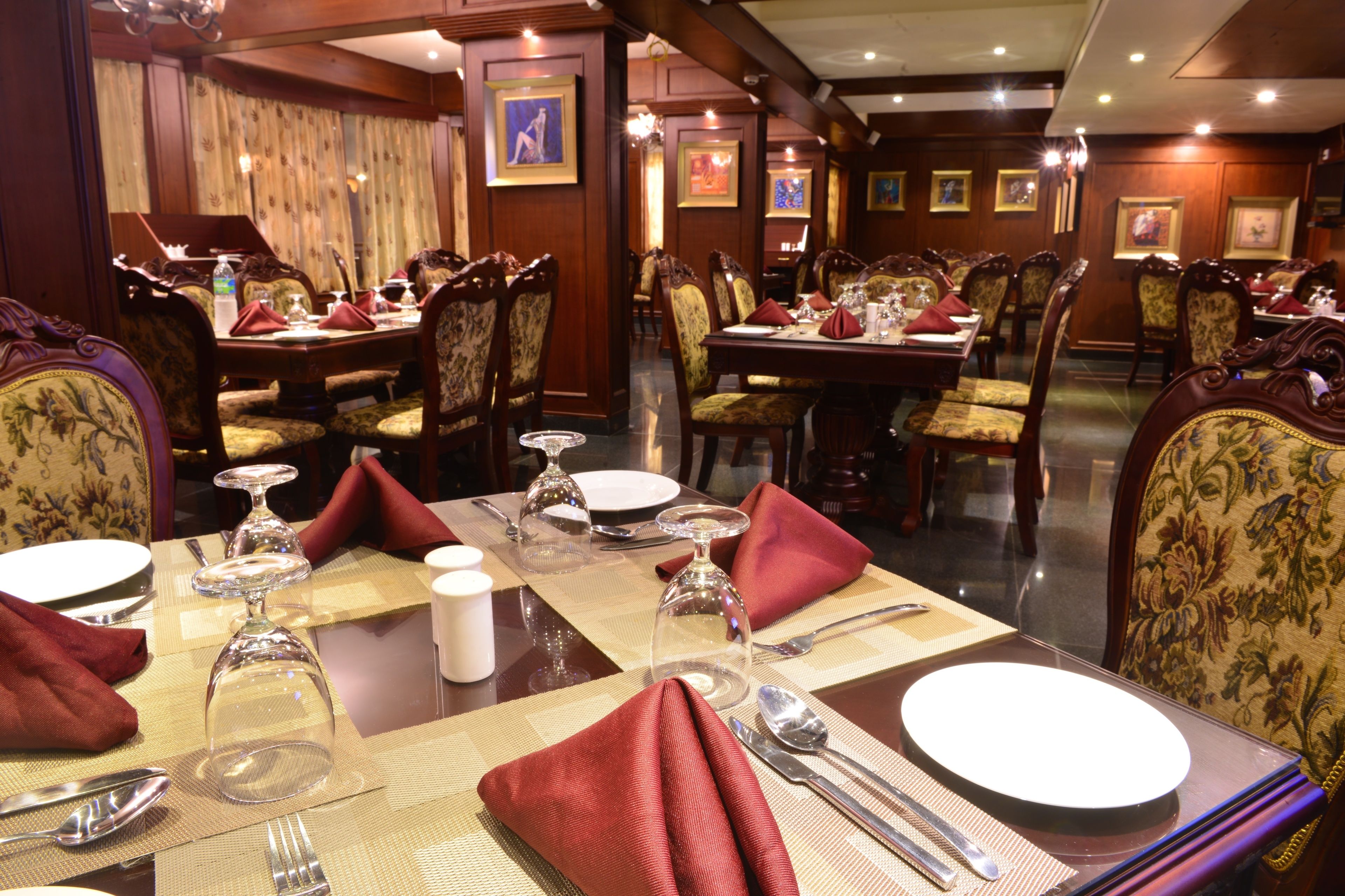 A formal dining area with multiple tables set for service, each with fine china, silverware, and glassware.