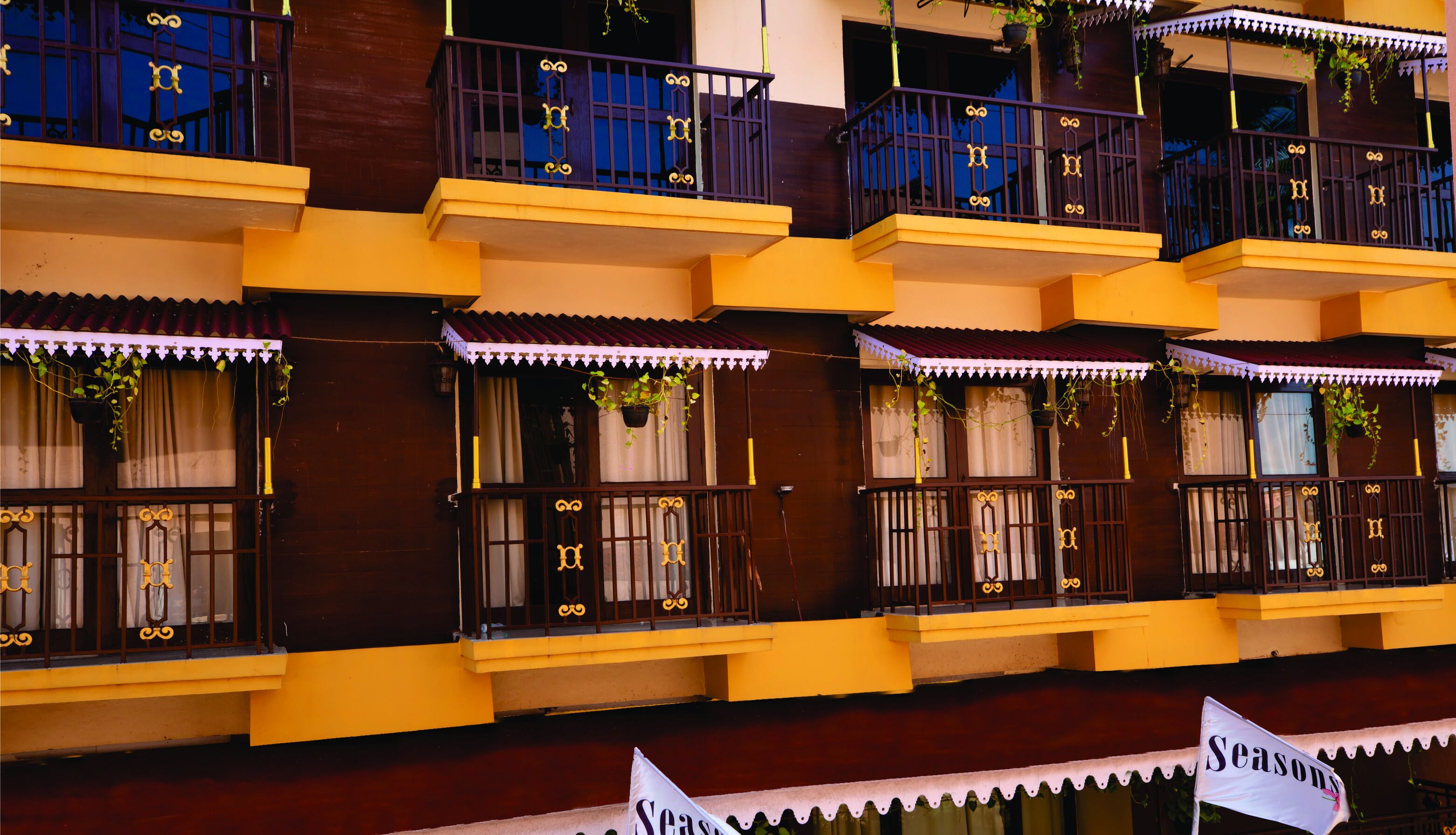 A multi-story building with balconies, each with decorative railings and potted plants.