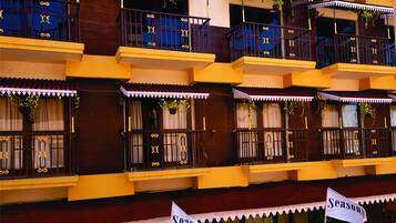 A multi-story building with balconies, each with decorative railings and potted plants.