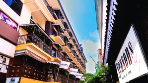 Un hotel de varios pisos con balcones, un cartel de Seasons Hotel & Spa, y una señalización visible de un restaurante.