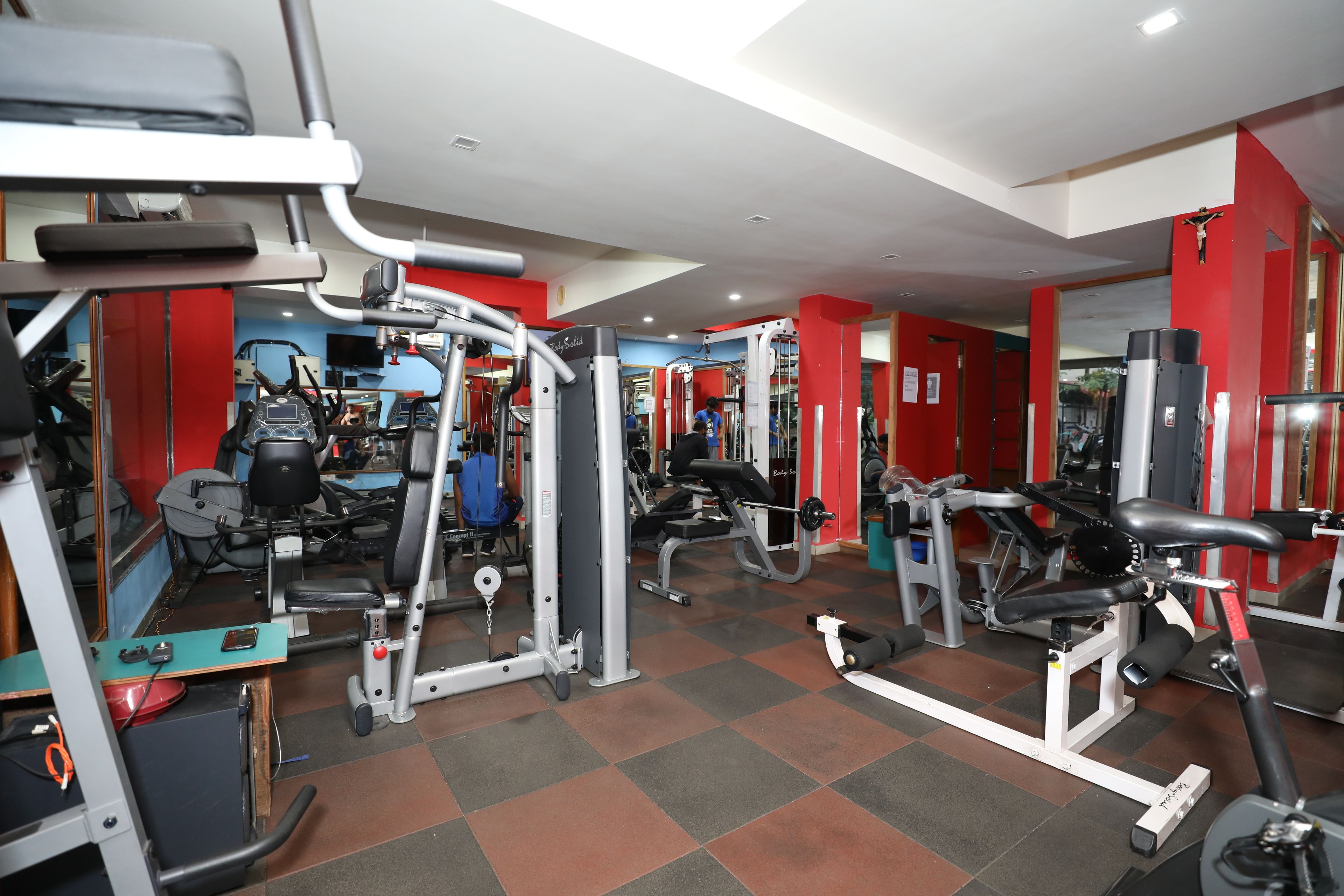 A gym with various exercise equipment, including treadmills, weight machines, and free weights.