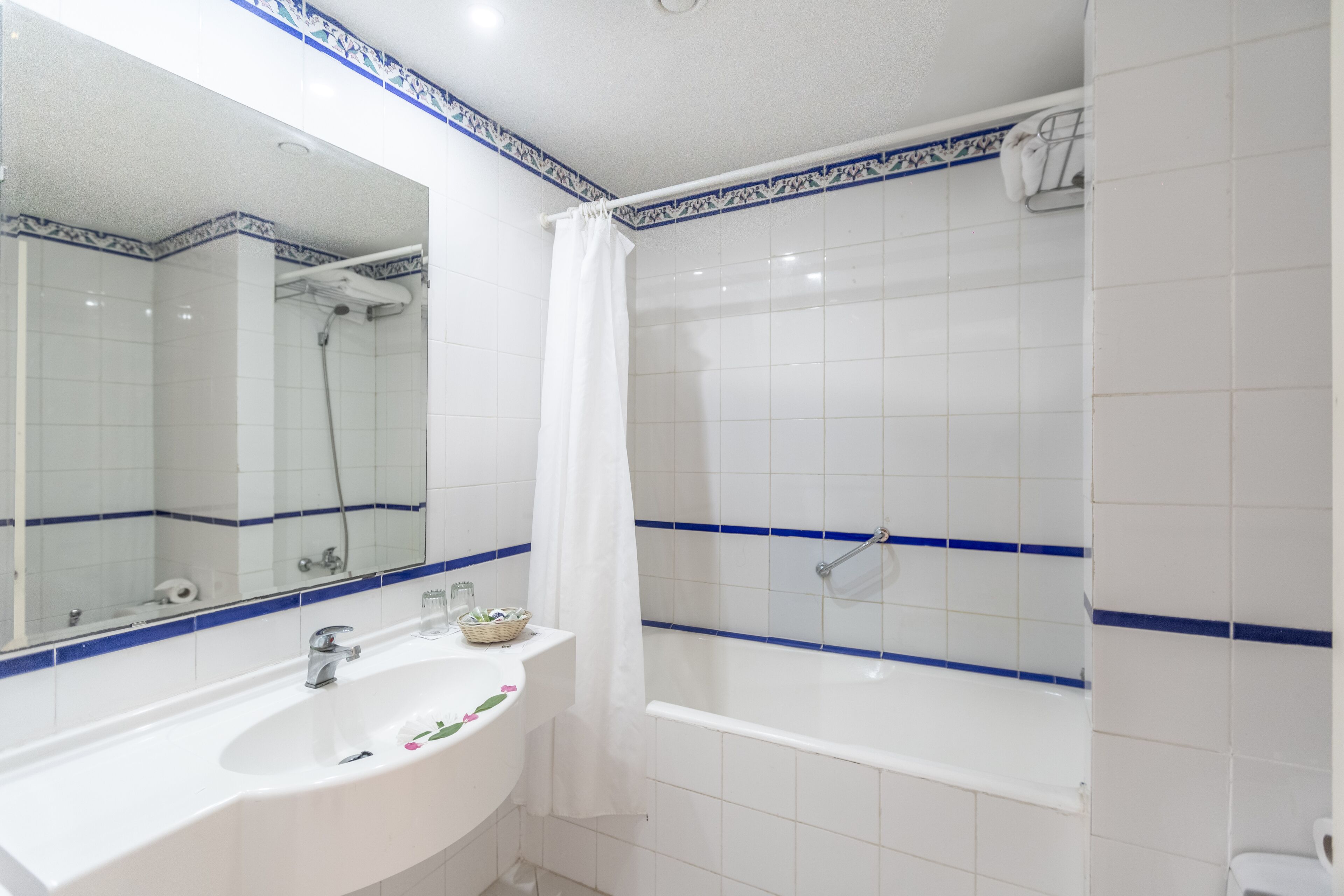 Un baño con lavamanos blanco, espejo y bañera.