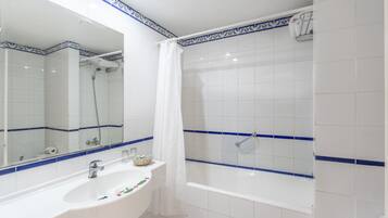 Un baño con lavamanos blanco, espejo y bañera.