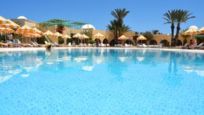 A swimming pool with lounge chairs and umbrellas, surrounded by palm trees and a clear sky. - Hotel Venice Beach - Families and Couples Only (Djerba Midun)