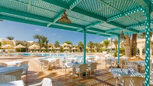 A poolside area with sun loungers and tables, a clear blue sky, and palm trees. - Hotel Venice Beach - Families and Couples Only (Djerba Midun)