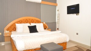Una habitación de hotel con una cama grande, un televisor montado en la pared y aire acondicionado integrado.