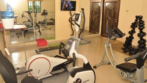 Un gimnasio con máquinas de cardio, equipo de levantamiento de pesas y una pantalla de televisión.