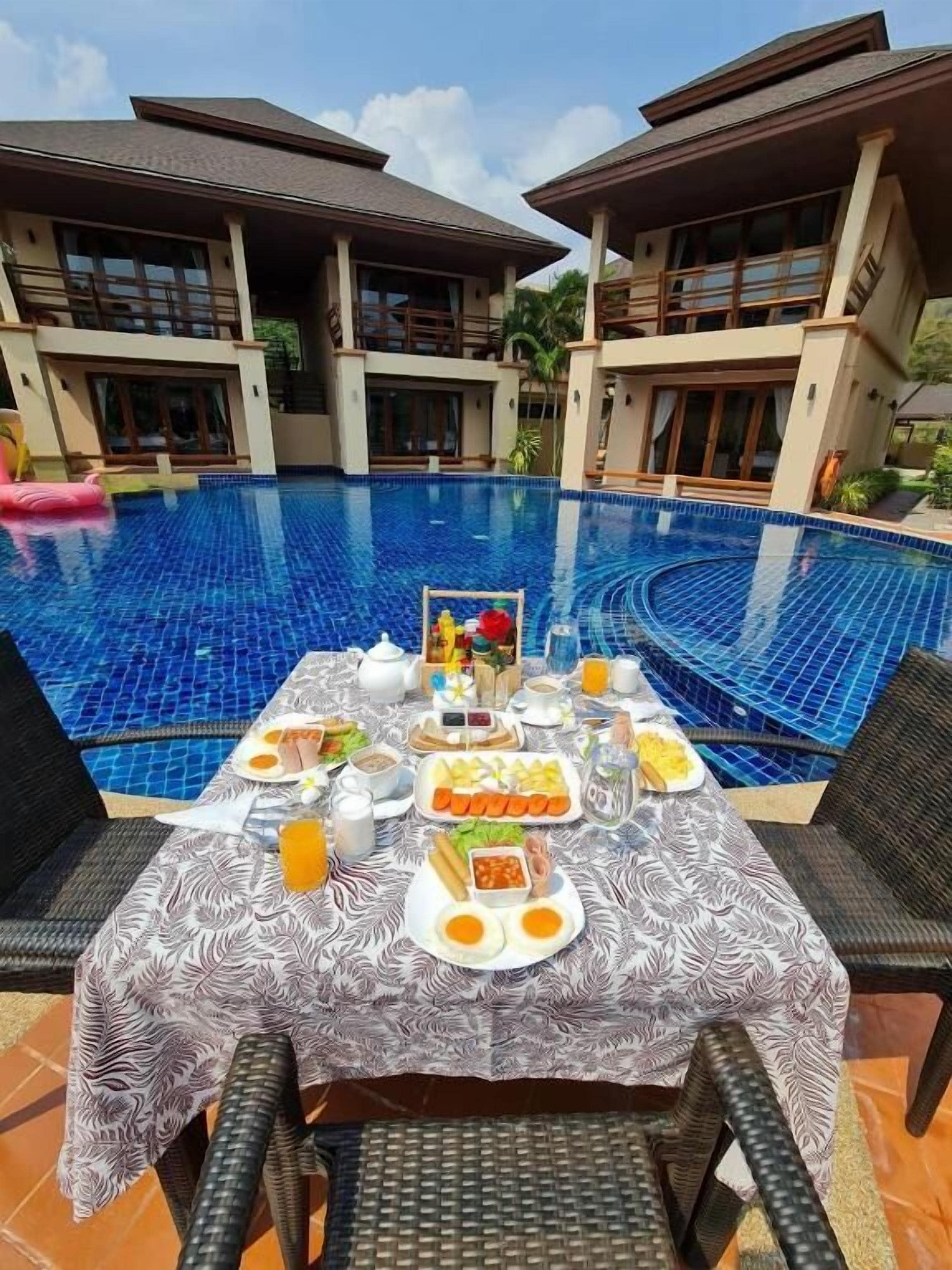 A dining table set for breakfast with a pool in the background.