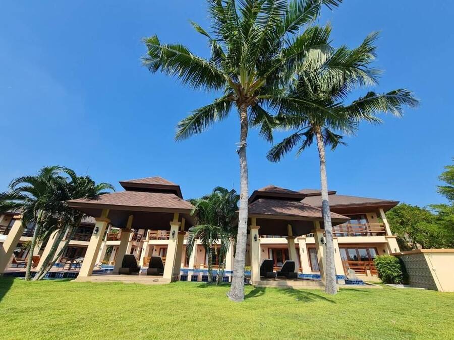 Un hotel con varios pisos, mobiliario exterior y palmeras.